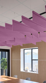 Purple angled acoustic baffles suspended from ceiling in modern office space with wood paneling and windows.