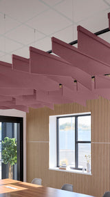 Angled burgundy acoustic baffles suspended from ceiling in modern office space above wooden wall paneling.