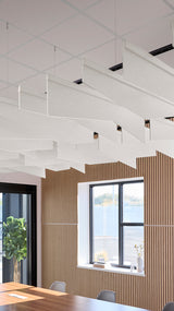 White angled acoustic baffles suspended from ceiling in modern office space with wooden wall panels.