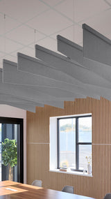 Gray angled acoustic baffles suspended from ceiling in modern office space with wood wall paneling.