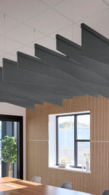 Five dark gray angled acoustic baffles suspended from ceiling above wooden wall paneling in an office space.