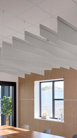 Gray fabric acoustic baffles suspended from ceiling grid in angled arrangement above wooden wall paneling.