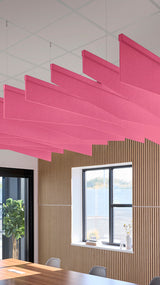 Pink angled acoustic baffles suspended from ceiling in modern office space with wood paneling and window.