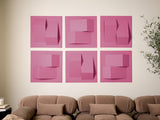 Six pink dimensional tiles with geometric cutouts and raised elements arranged in a grid on a wall above a brown sofa.