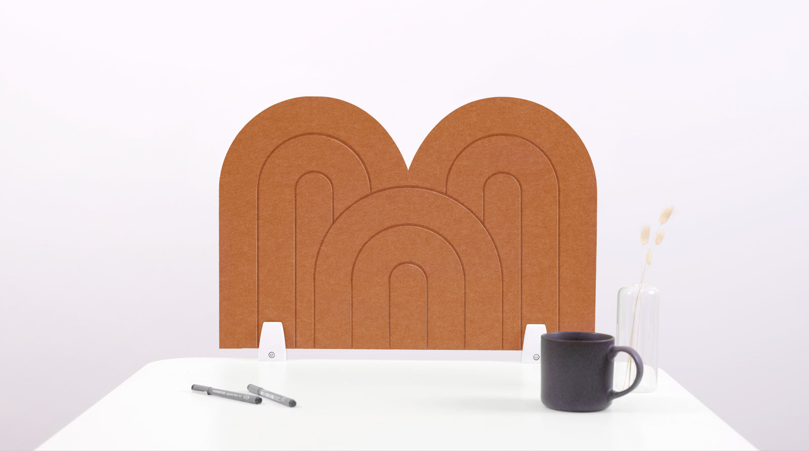 A cinnamon colored felt desk divider with a scalloped design of lines and arches. 