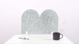 A nickel colored arch-shaped desk divider on a white desk. For the side of your desk.