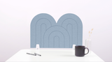 A light blue arch-shaped desk divider on a white desk. For the side of your desk.