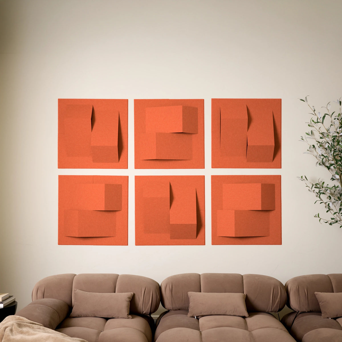 Orange acoustic felt tiles with points of dimension on a wall above a brown couch