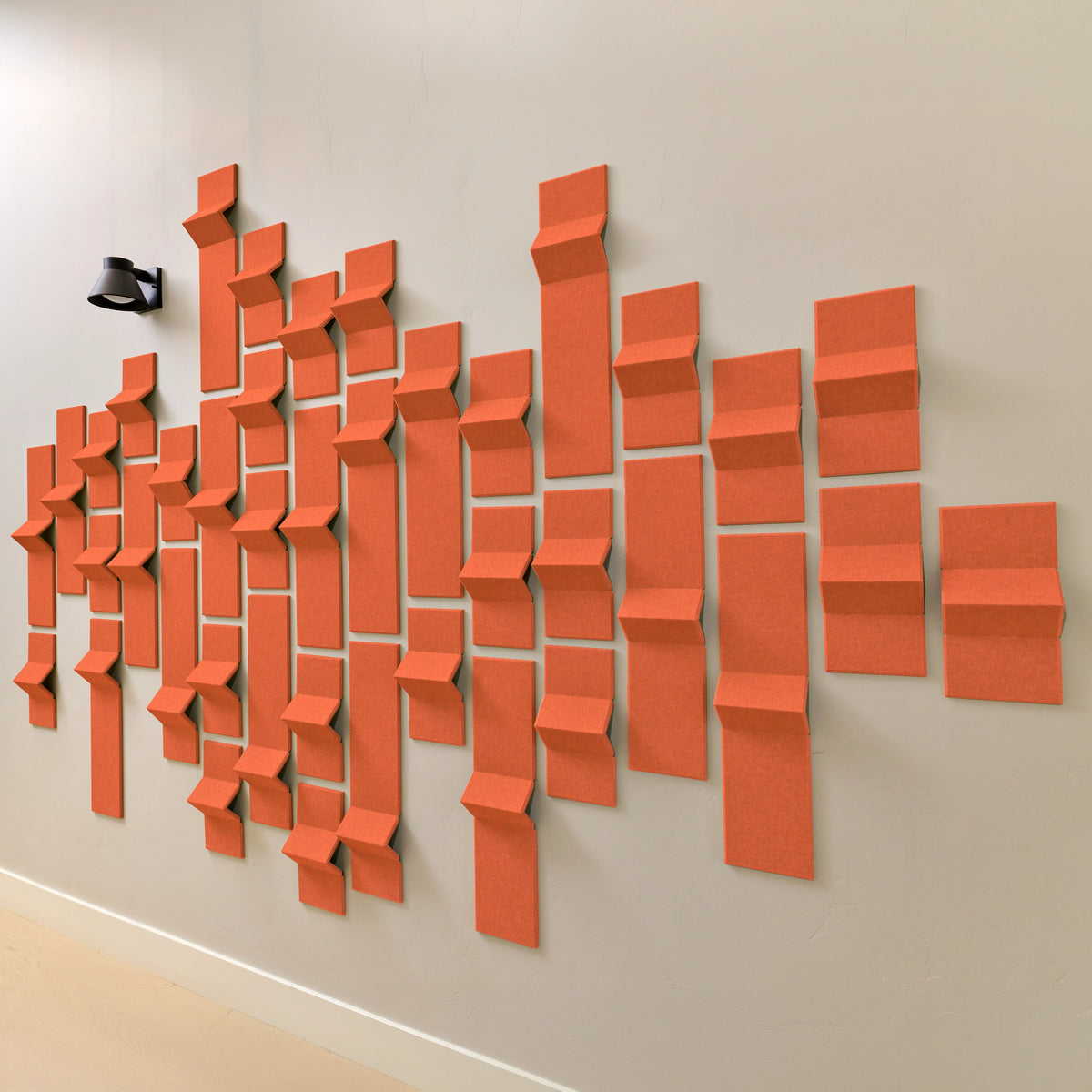 Orange acoustic felt tiles with 3d peaks along a wall