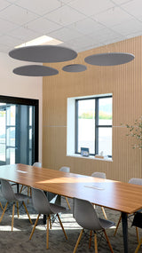 Four dark gray oval ceiling baffles suspended at varying heights above a conference table in a modern office space.