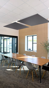 Two black square acoustic baffles suspended from ceiling grid above conference table in modern office space.