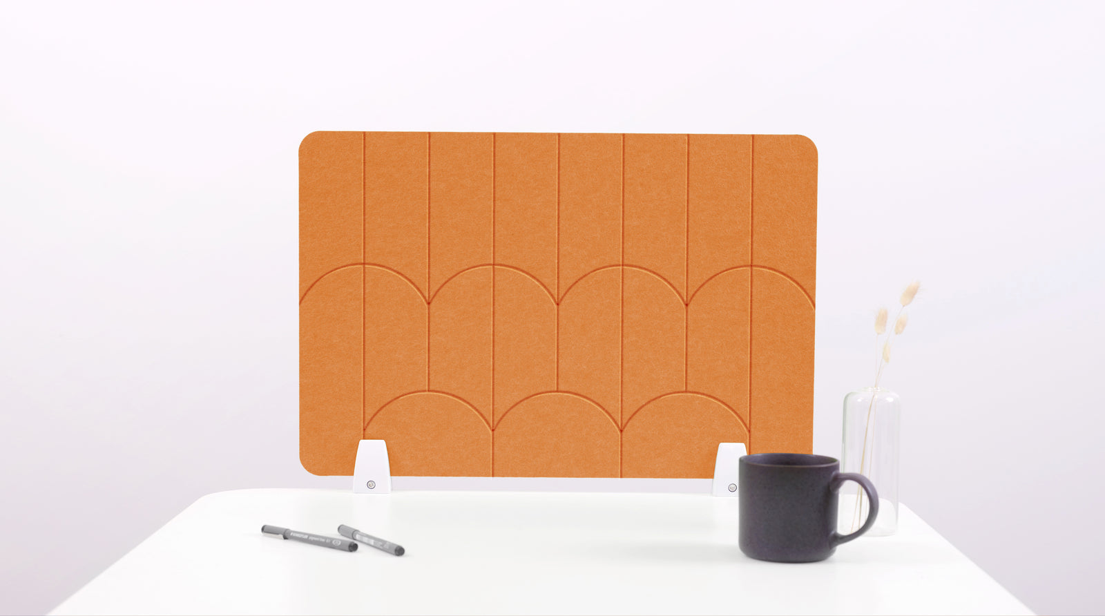 An orange colored felt desk divider with a scalloped design of lines and arches. 