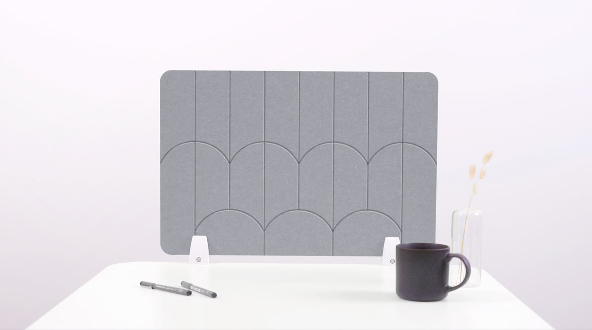 A gray felt desk divider with a scalloped design of lines and arches. 