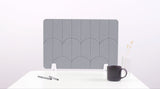 A gray felt desk divider with a scalloped design of lines and arches. 
