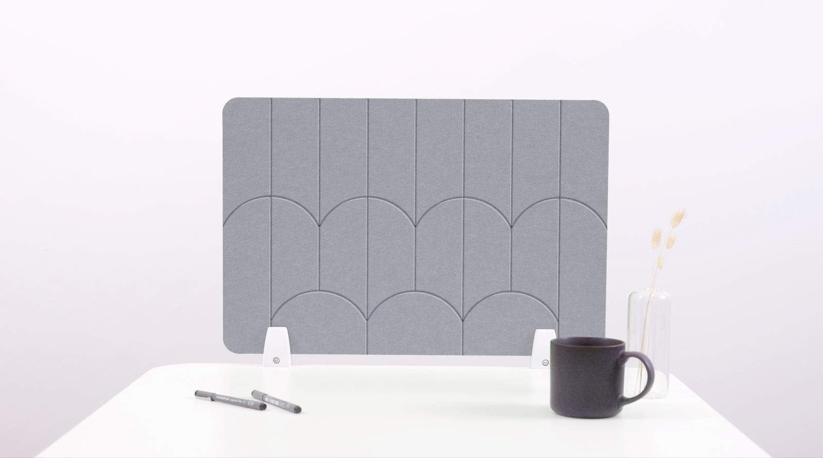 A gray felt desk divider with a scalloped design of lines and arches. 