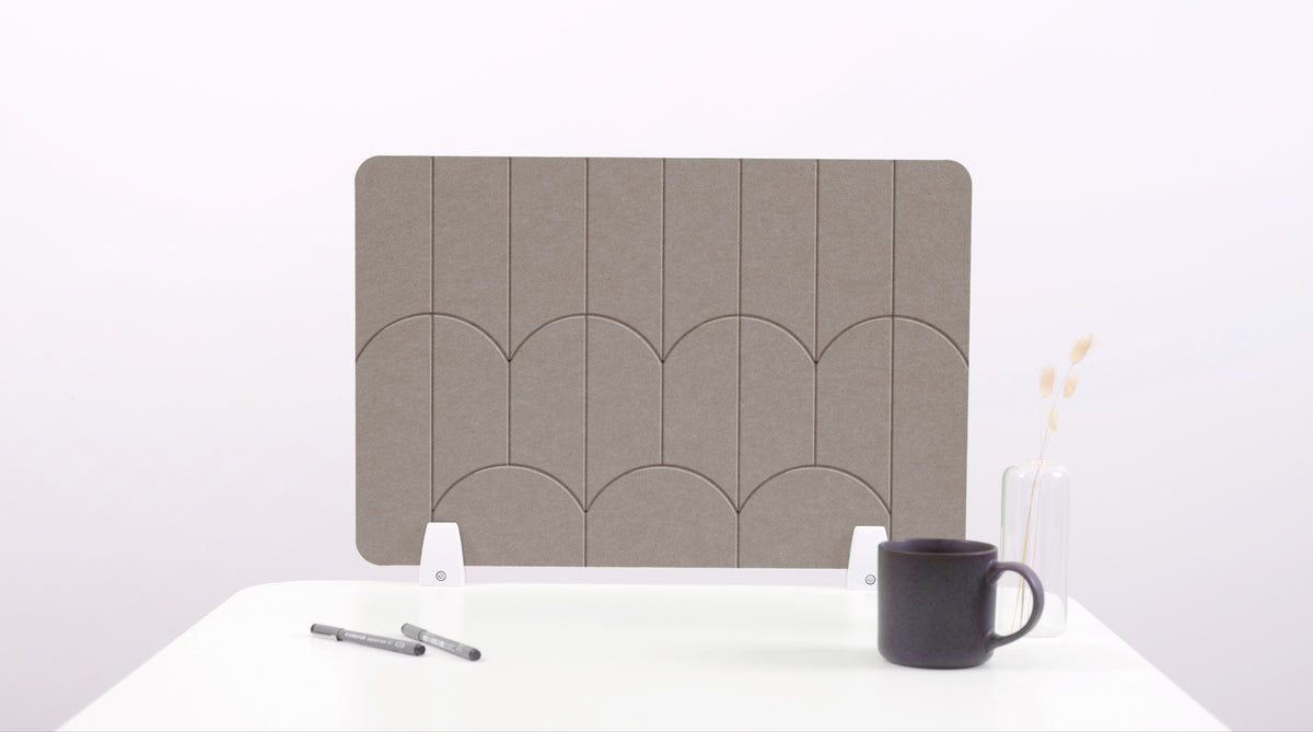 A brown colored felt desk divider with a scalloped design of lines and arches. 