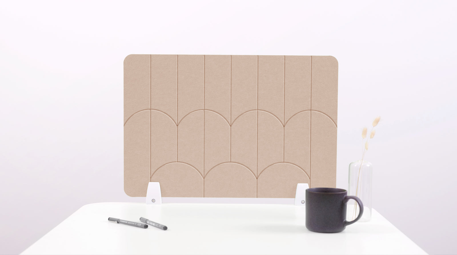 A tan colored felt desk divider with a scalloped design of lines and arches. 