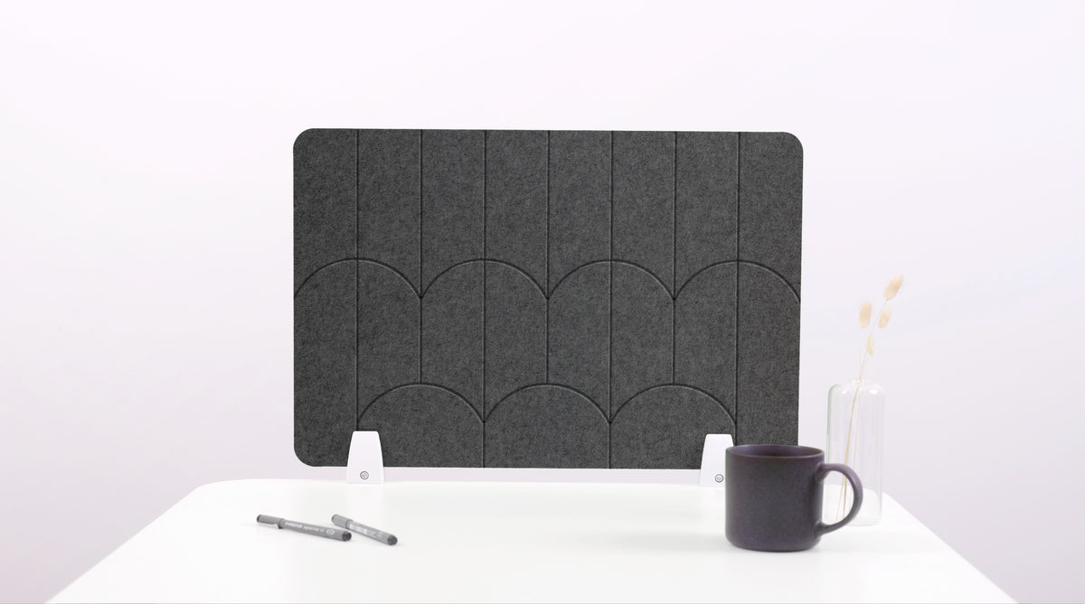 A dark gray felt desk divider with a scalloped design of lines and arches. 