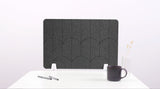 A dark gray felt desk divider with a scalloped design of lines and arches. 