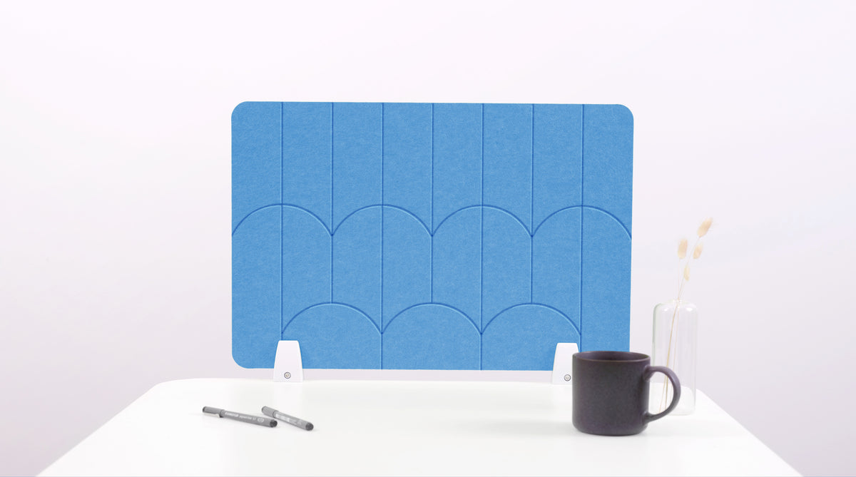 A light blue colored felt desk divider with a scalloped design of lines and arches. 