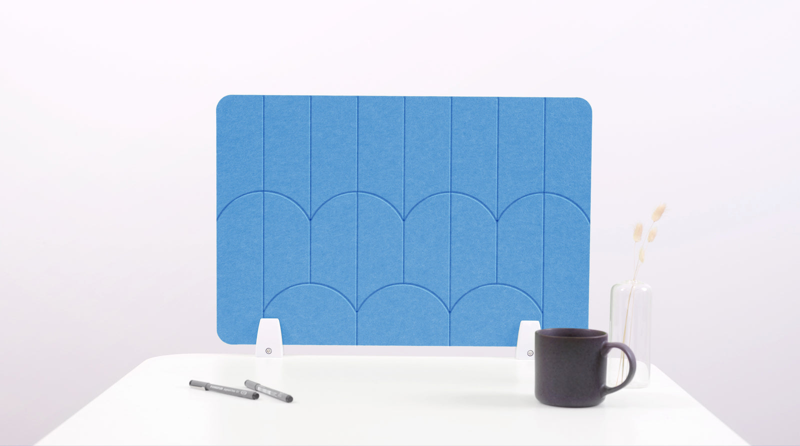 A light blue colored felt desk divider with a scalloped design of lines and arches. 