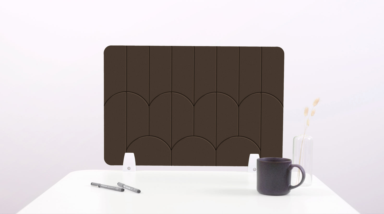 A dark brown colored felt desk divider with a scalloped design of lines and arches.