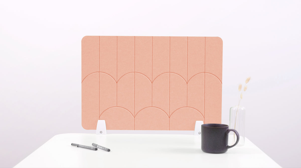 A peach colored felt desk divider with a scalloped design of lines and arches.