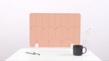 A peach colored felt desk divider with a scalloped design of lines and arches.