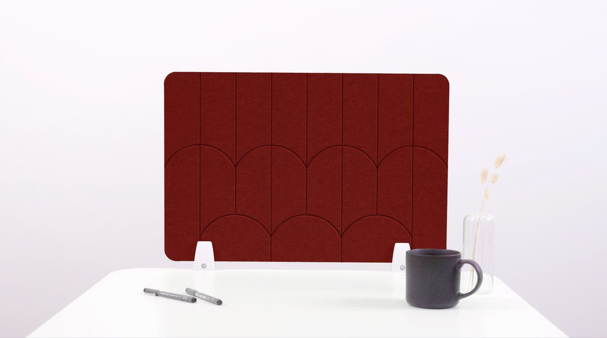 A red colored felt desk divider with a scalloped design of lines and arches. 