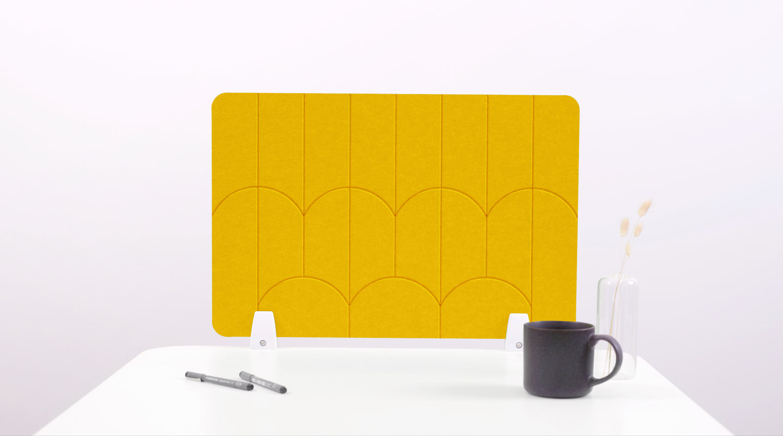 A yellow colored felt desk divider with a scalloped design of lines and arches. 