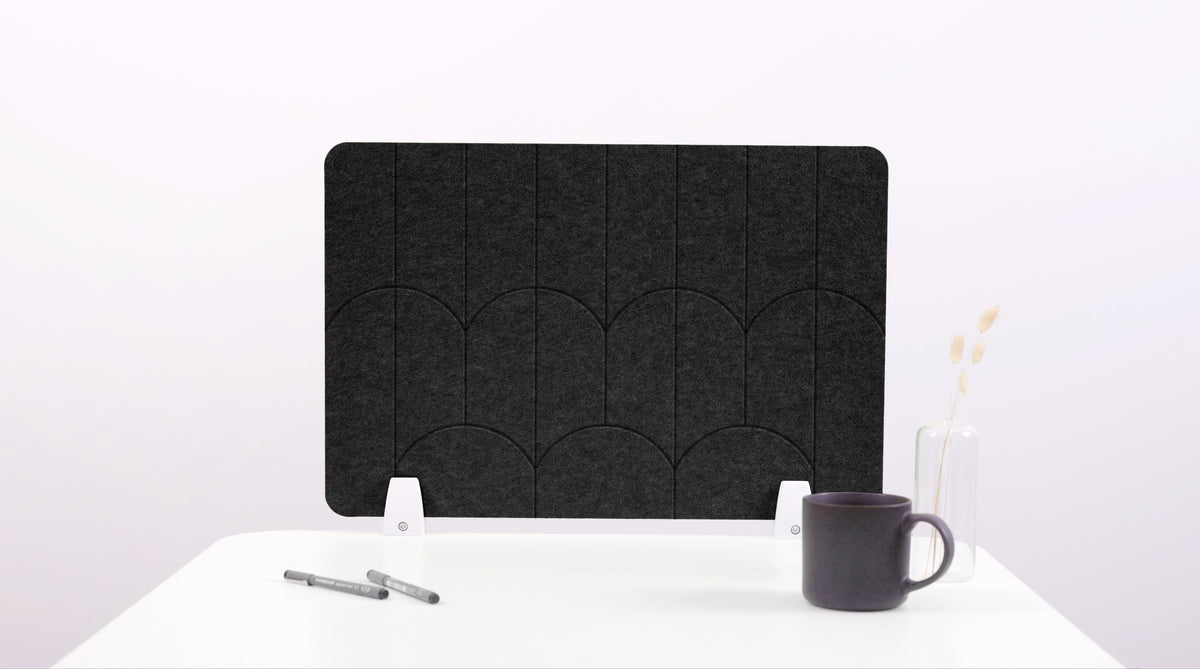 A black felt desk divider with a scalloped design of lines and arches. 