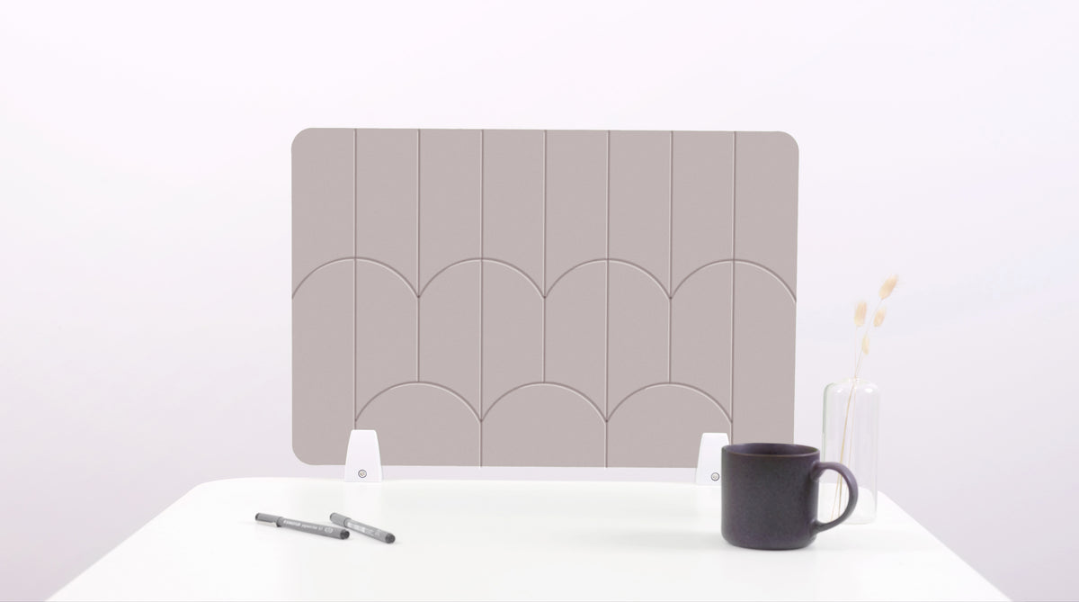 A tan colored felt desk divider with a scalloped design of lines and arches. 