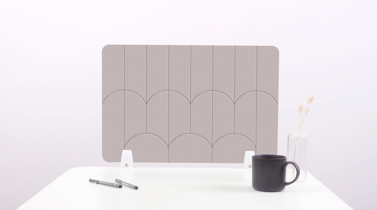 A tan colored felt desk divider with a scalloped design of lines and arches. 