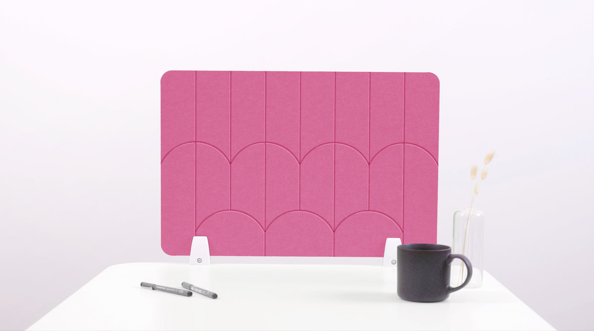 A pink felt desk divider with a scalloped design of lines and arches. 