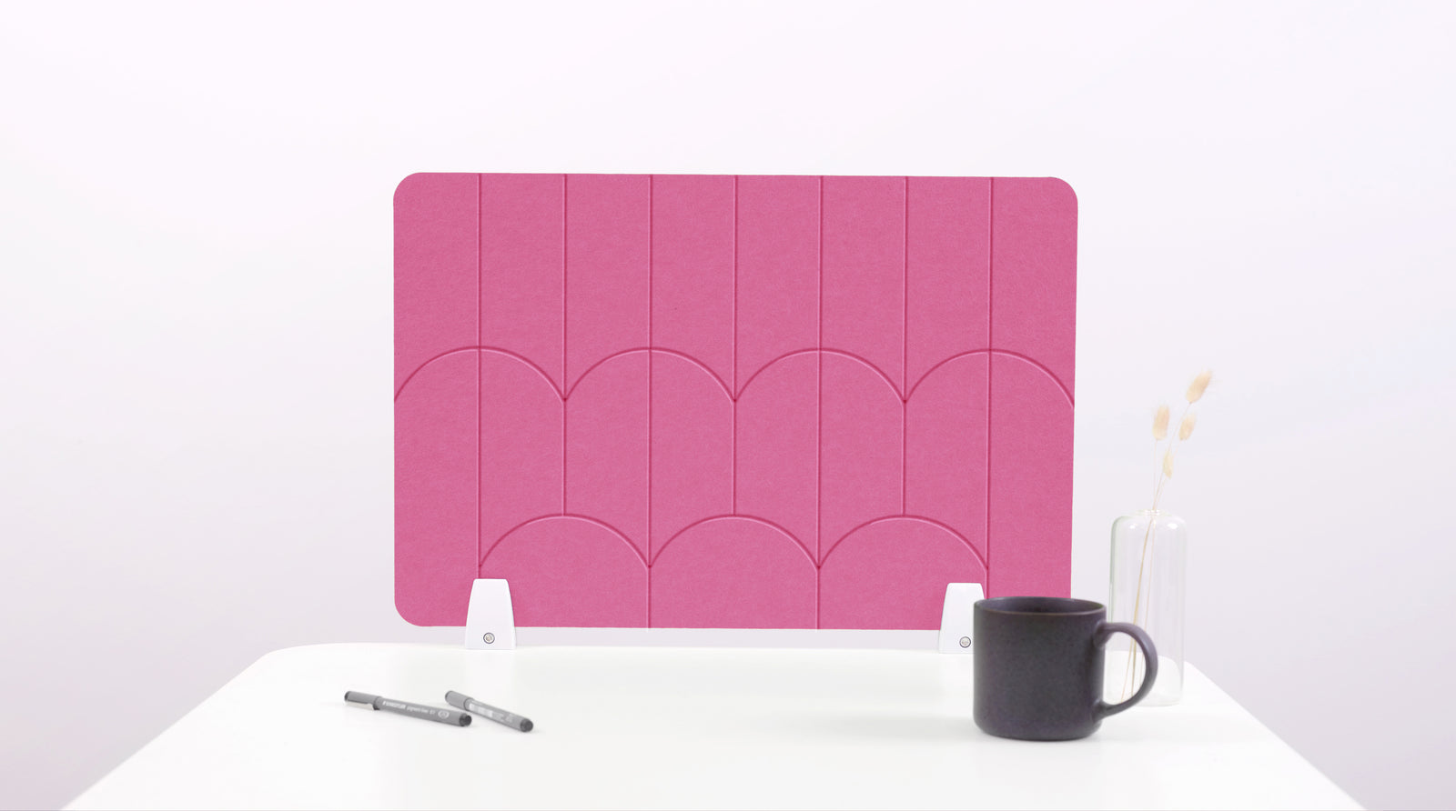 A pink felt desk divider with a scalloped design of lines and arches. 