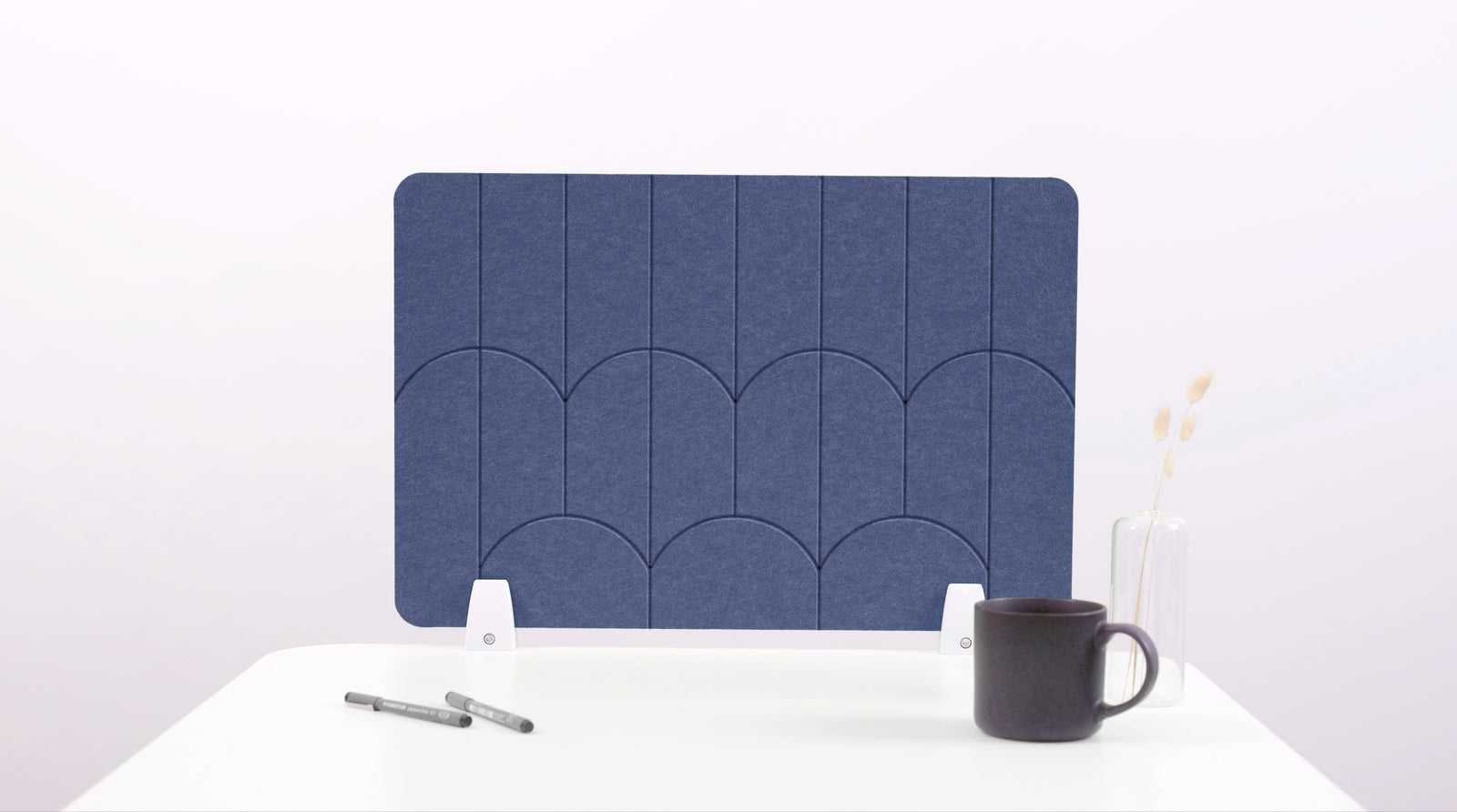 A indigo blue colored felt desk divider with a scalloped design of lines and arches. 