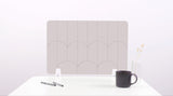 A white colored felt desk divider with a scalloped design of lines and arches. 
