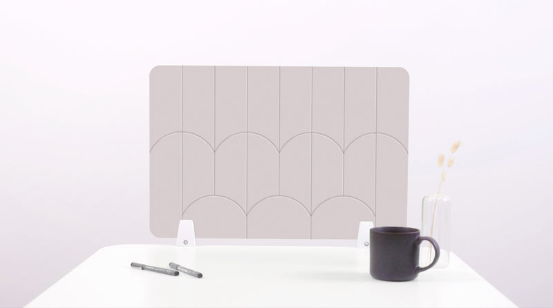 A white colored felt desk divider with a scalloped design of lines and arches. 