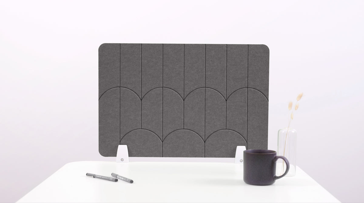 A dark gray felt desk divider with a scalloped design of lines and arches. 