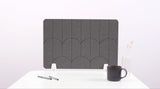 A dark gray felt desk divider with a scalloped design of lines and arches. 