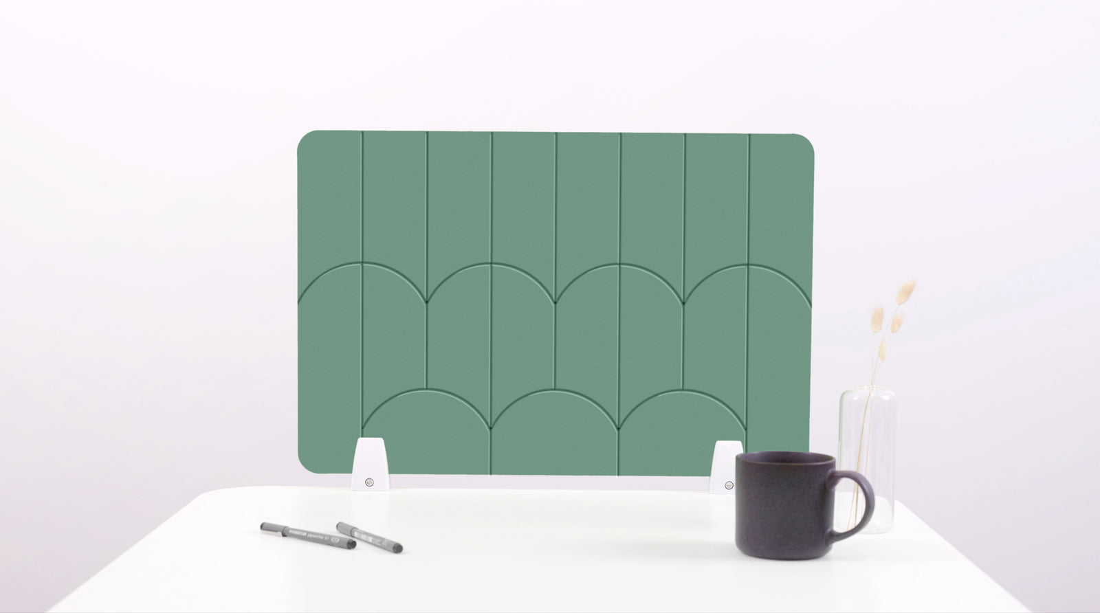 A mint green colored felt desk divider with a scalloped design of lines and arches. 