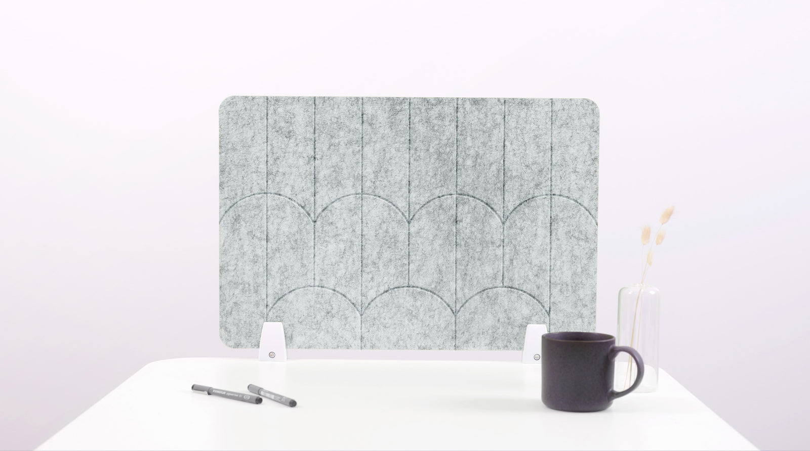 A nickel colored felt desk divider with a scalloped design of lines and arches. 