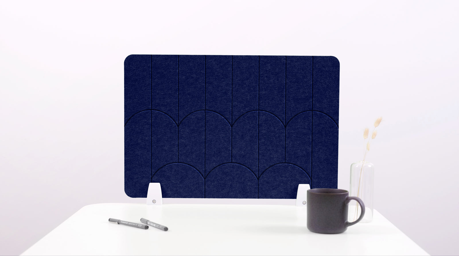 A navy blue colored felt desk divider with a scalloped design of lines and arches. 
