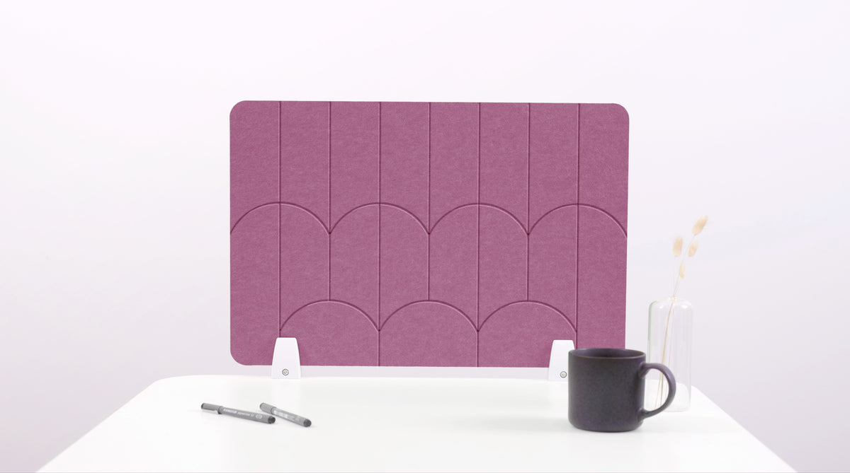 A pink colored felt desk divider with a scalloped design of lines and arches. 