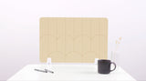 A light tan colored felt desk divider with a scalloped design of lines and arches. 