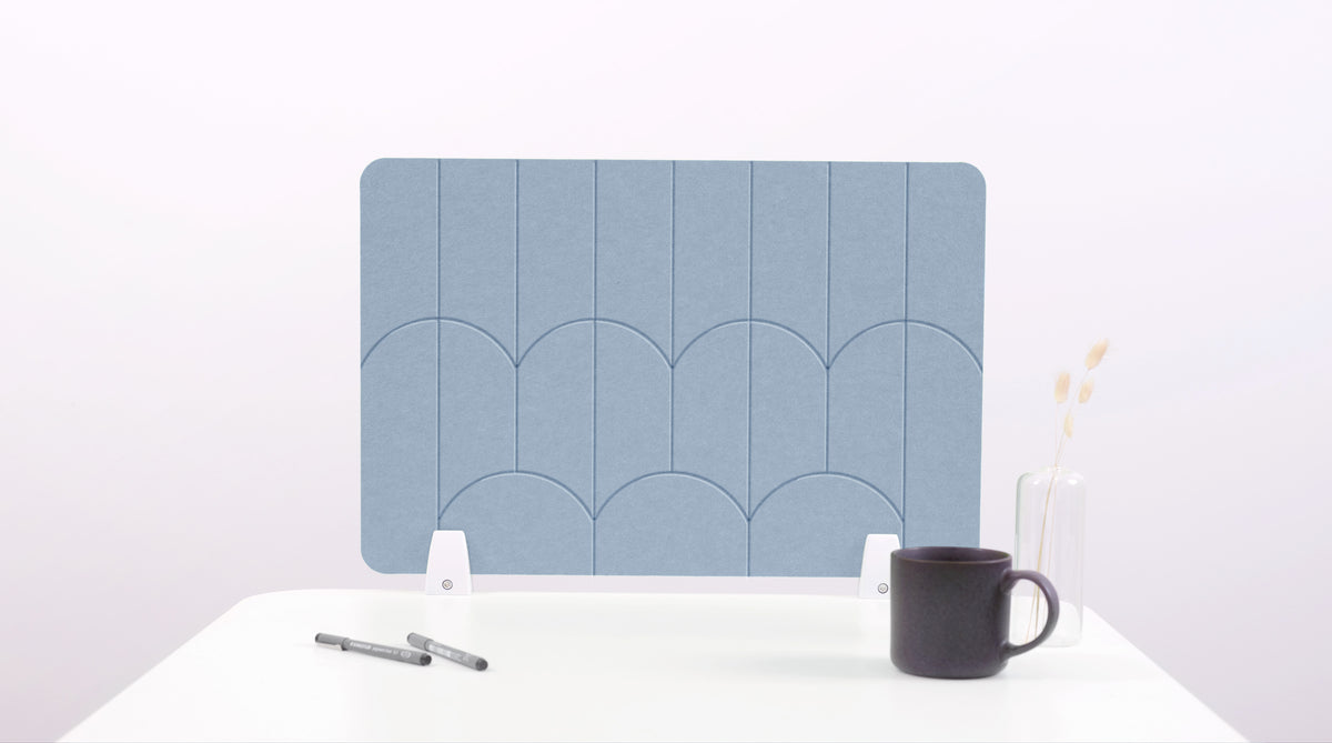 A powder blue colored felt desk divider with a scalloped design of lines and arches. 