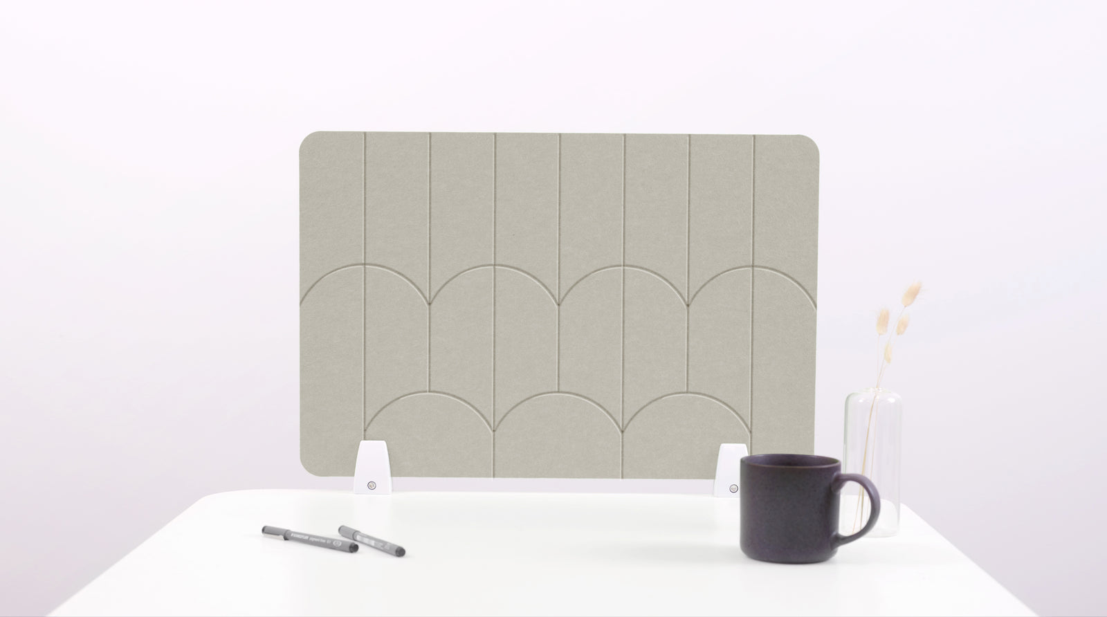 A faded green colored felt desk divider with a scalloped design of lines and arches. 