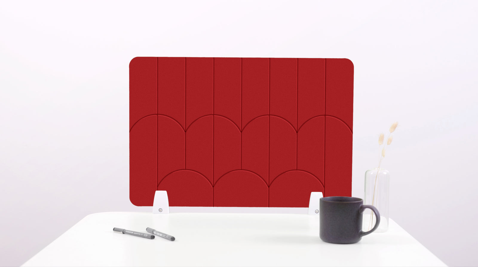 A red colored felt desk divider with a scalloped design of lines and arches. 