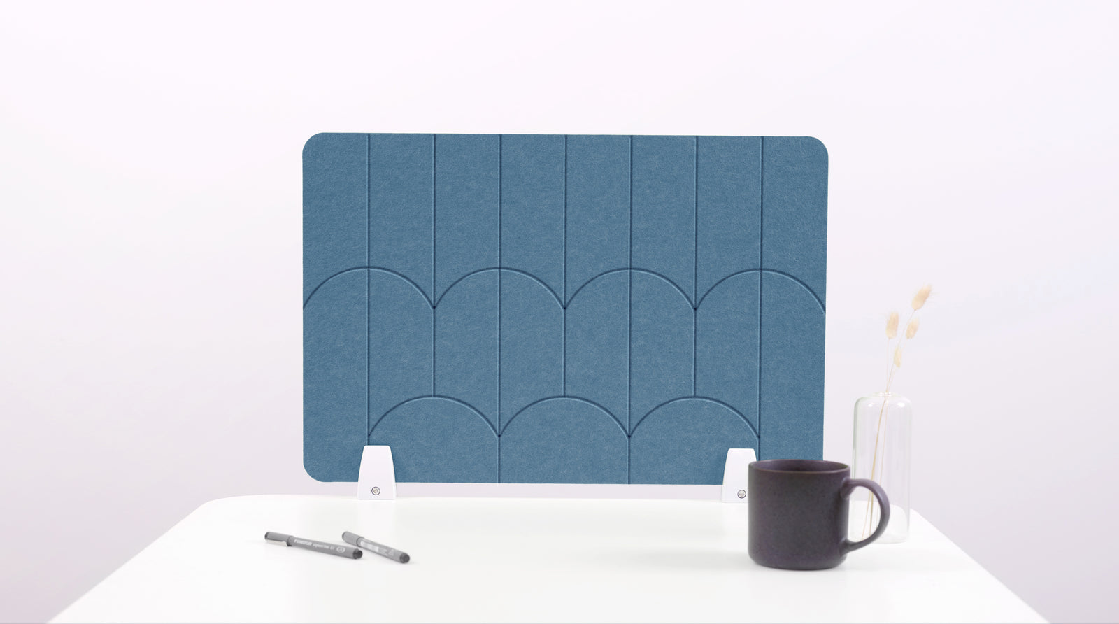 A slate blue colored felt desk divider with a scalloped design of lines and arches. 