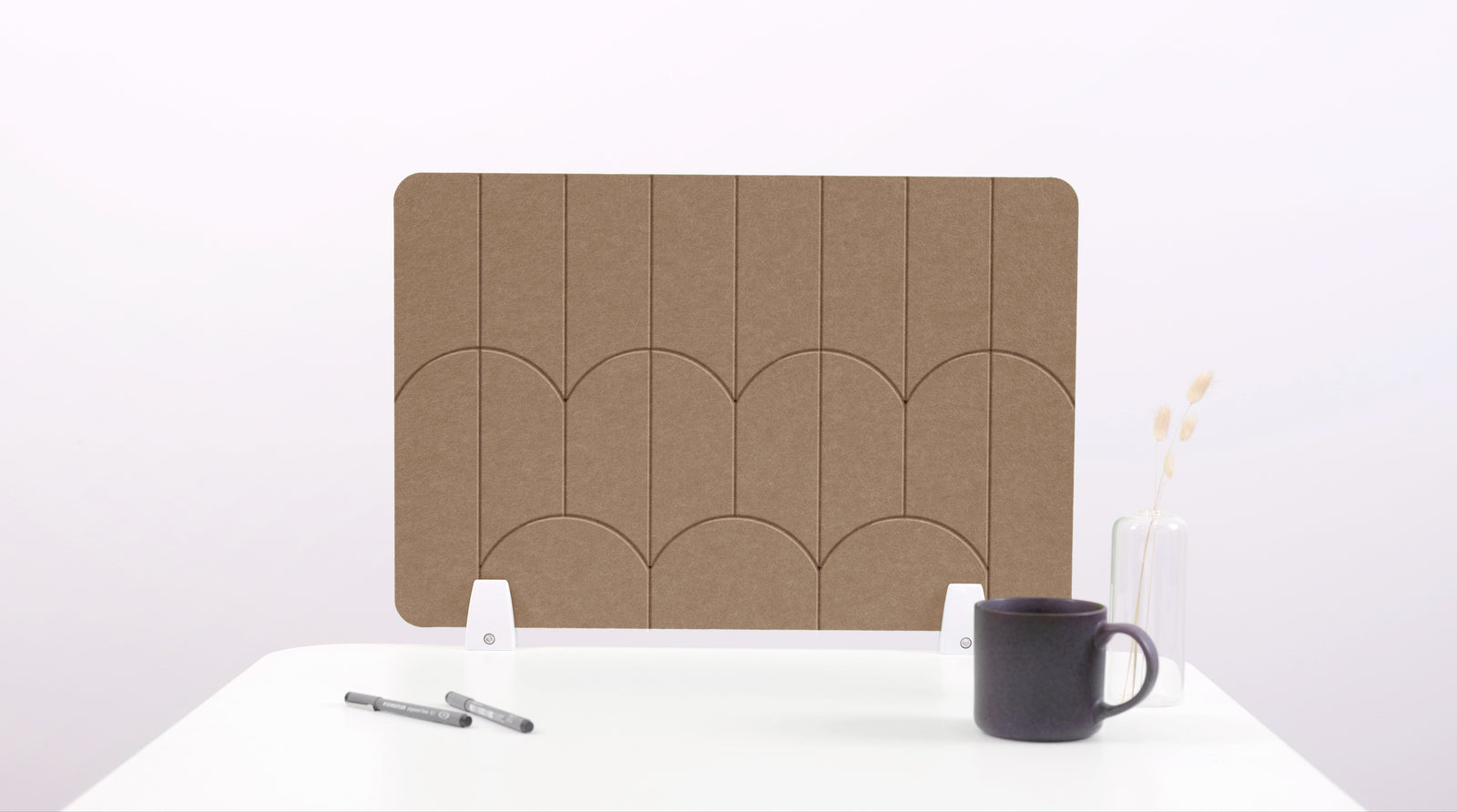A brown colored felt desk divider with a scalloped design of lines and arches. 
